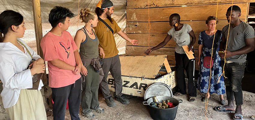 Students from the D-Lab class Applications of Energy in Global Development with mentors and community partners from DAS-BC (African Diaspora Council of Switzerland) in Cameroon standing by their first low-cost brooder box and one load of beeswax thermal batteries. From left to right: Megan Harvey '25, Tyler Ea '25, Kristine Januskaite (trip leader), Ahmad Zakka SM'23 (trip leader), Carole Erlemann Mengue (founder of CDAS-BC), Kathrin Witschi (founder of CDAS-BC), and an intern.