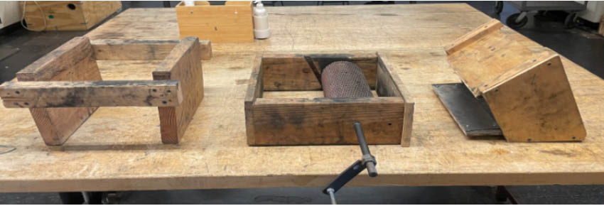 Three wood and metal objects on a a work table.