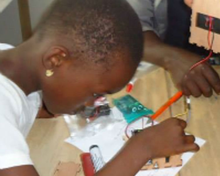 Netia assisting a young participant in assembling her Solar USB Charger at a Mbadika Workshop in Cape Town, South Africa.