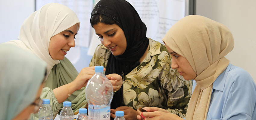 Three women in headscarves, their heads close together looking at something.